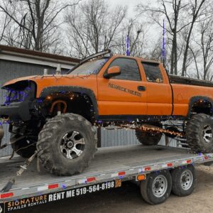 Orange monster truck decorated with colorful lights.