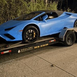 Blue sports car on a trailer at night.