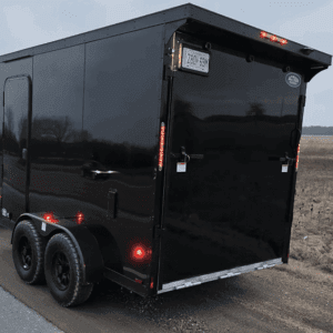 Black trailer hitched to a vehicle roadside.