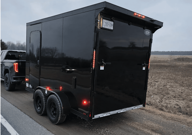 Black trailer hitched to a vehicle roadside.
