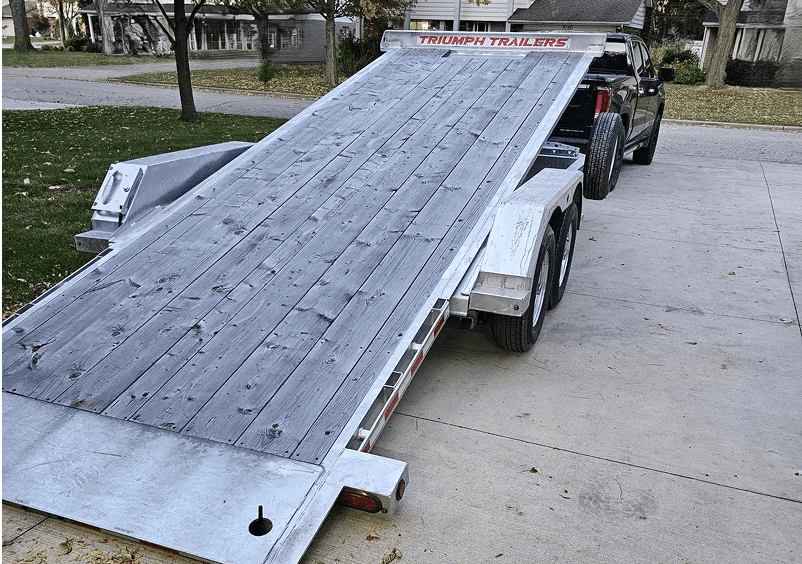 Truck with raised Triumph trailer on driveway.
