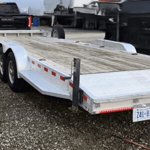 Flatbed trailer parked on gravel surface.