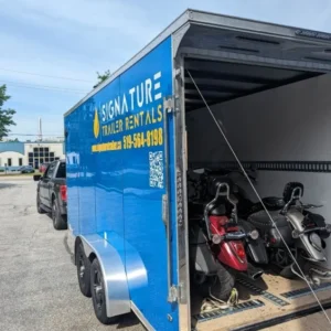 Blue trailer with scooters inside, parked outside.