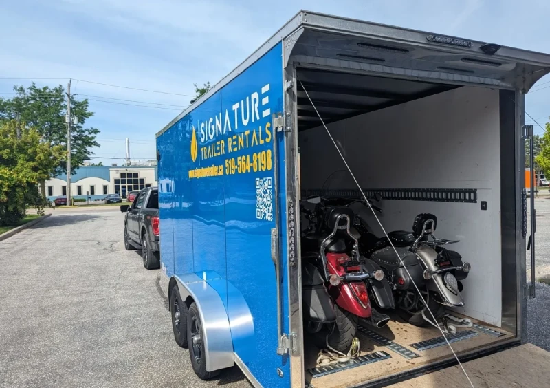 Blue trailer with scooters inside, parked outside.