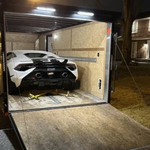 Car secured inside an open transport trailer.