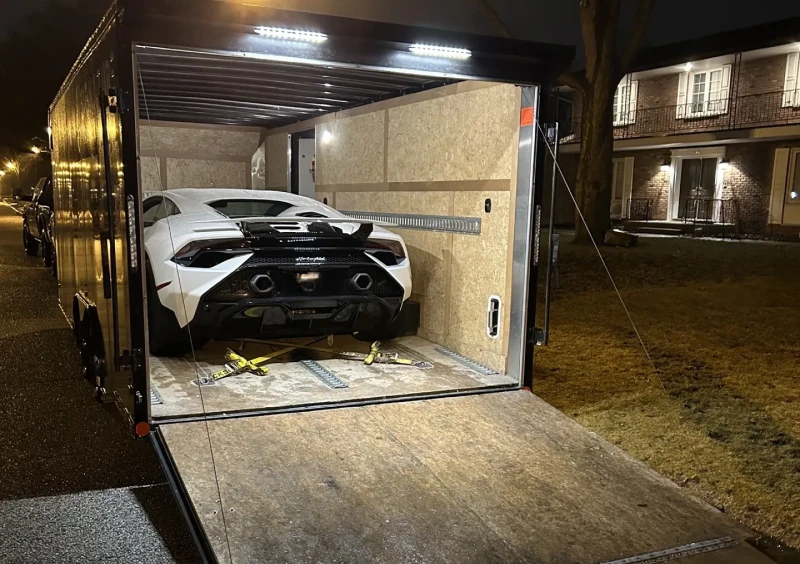 Car secured inside an open transport trailer.